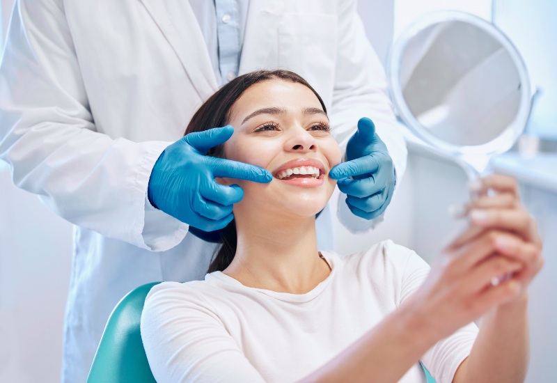A dentist examines a woman’s teeth during a follow-up after restorative treatment in Charles Town.