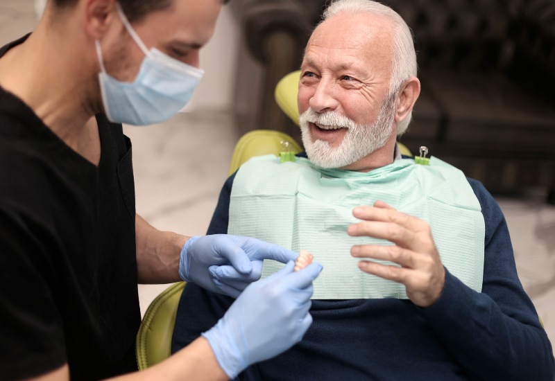 A man in a dental chair discusses partial and full dentures with an older man in Charles Town, WV.
