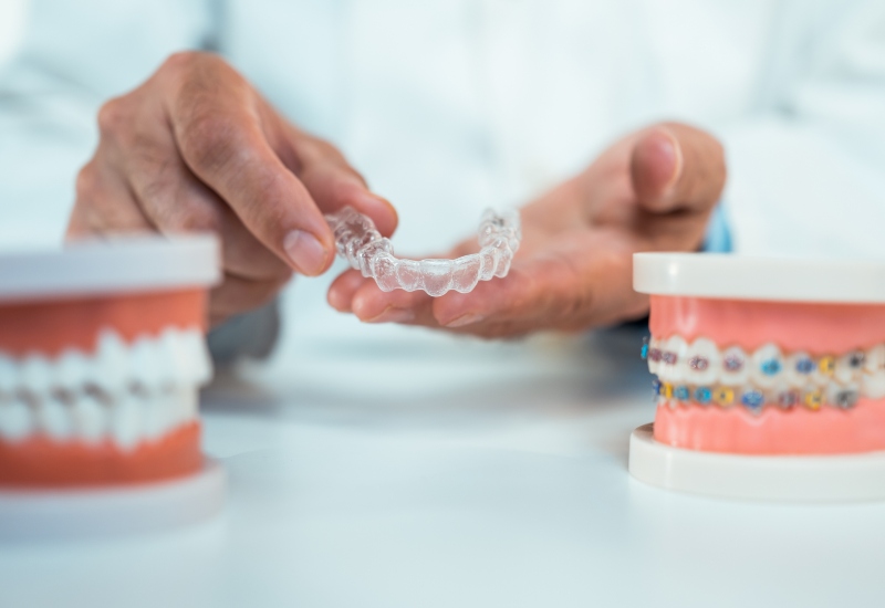 A person holds a clear aligner, emphasizing Invisalign Treatment in Charles Town, WV.