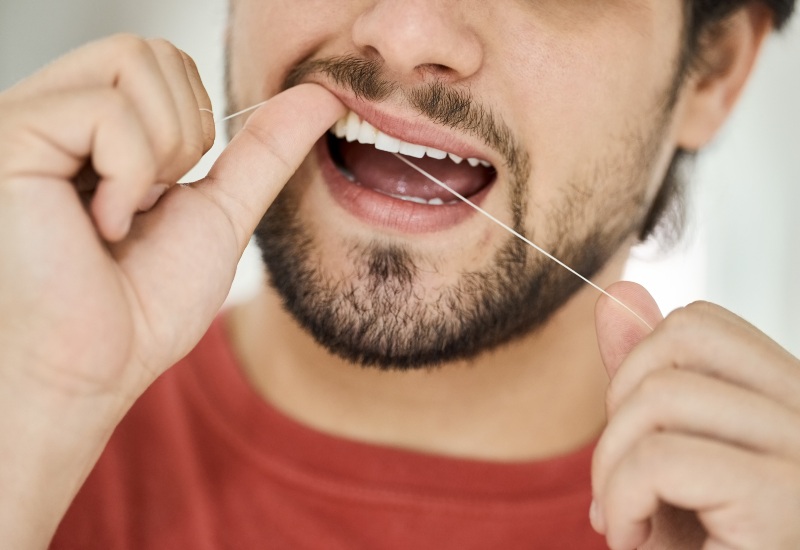 A man flossing his teeth, highlighting the importance of flossing in Charles Town, WV