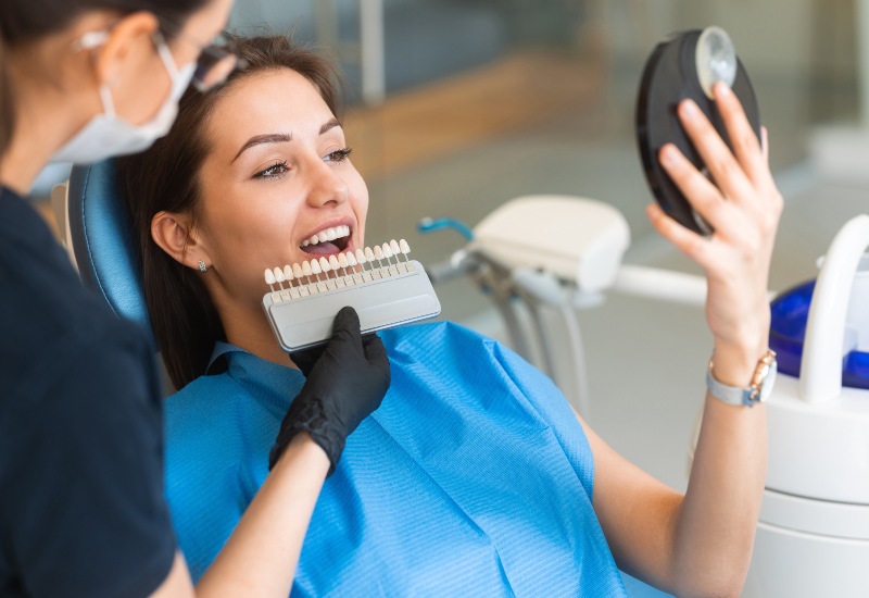 A dentist assisting a patient with porcelain veneers shade matching in a clinic in Charles Town, WV