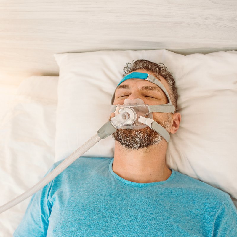 A man sleeping with a CPAP machine in a bedroom for sleep apnea treatment in Charles Town, WV